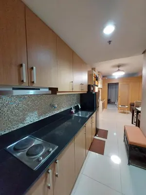 a kitchen with wooden cabinets and a black counter top at She'll residences condotel in Manila