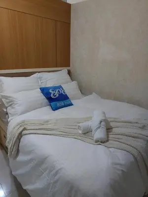 a white bed with a blue pillow on it at She'll residences condotel in Manila