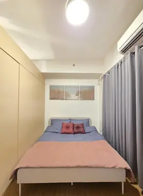 a bedroom with a large bed with a window at CL Urban Homestay Cozy 1BR near BGC & NAIA in Manila