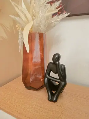 a statue of a person sitting on a shelf next to a vase at CL Urban Homestay Cozy 1BR near BGC & NAIA in Manila
