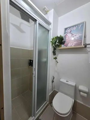 a bathroom with a toilet and a glass shower at CL Urban Homestay Cozy 1BR near BGC & NAIA in Manila