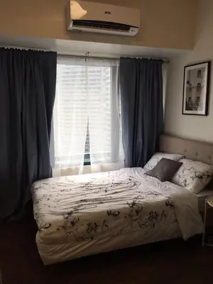 a bedroom with a bed and a window with curtains at Cozy & Affordable Stay in Air Residences in Manila