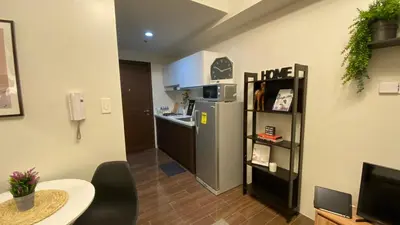 a small kitchen with a refrigerator and a table at Cozy & Affordable Stay in Air Residences in Manila