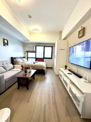 a living room with a large tv and a couch at Cozy Modern Studio Unit with PS4 at The Sentinel Residences, Cubao in Manila
