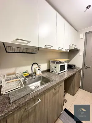 a kitchen with a sink and a microwave at Cozy Modern Studio Unit with PS4 at The Sentinel Residences, Cubao in Manila