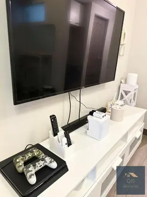 a living room with a tv and remote controls on a table at Cozy Modern Studio Unit with PS4 at The Sentinel Residences, Cubao in Manila