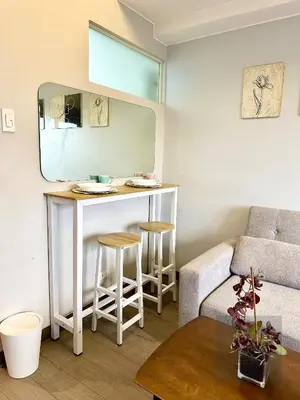 a small living room with a table and a mirror at Cozy Modern Studio Unit with PS4 at The Sentinel Residences, Cubao in Manila