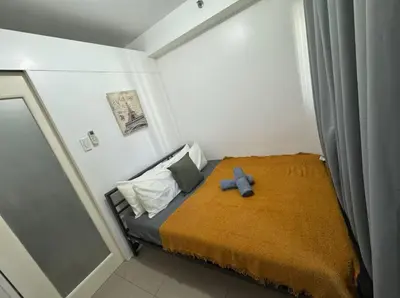 a small bedroom with a bed with a blue cross on it at At The Shore in Manila