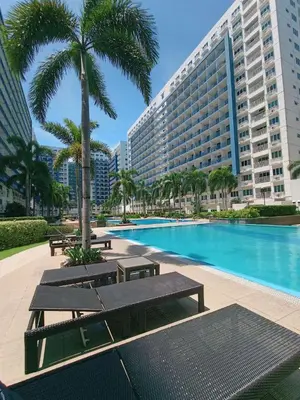 a swimming pool with benches and a large building at Staycation at Sea Residences MOA Pasay City in Manila