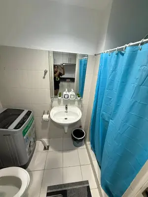 a man taking a picture of a bathroom with a sink at Staycation at Sea Residences MOA Pasay City in Manila