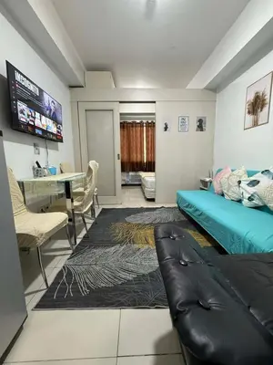 a room with a bed and a desk and a couch at Staycation at Sea Residences MOA Pasay City in Manila