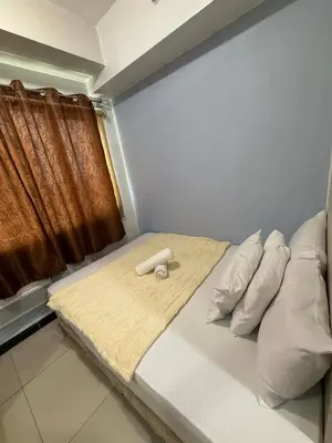 a bedroom with a bed with pillows and a window at Staycation at Sea Residences MOA Pasay City in Manila