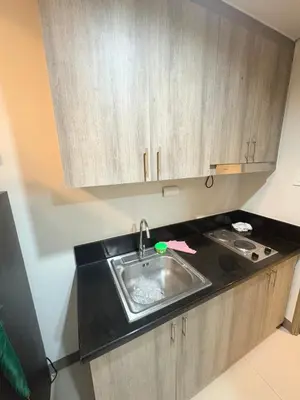 a kitchen with a sink and wooden cabinets at Seva Condo Residences in Manila