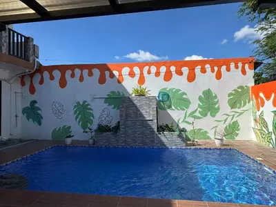 a swimming pool in front of a wall with a mural at Hidden Leaf Private Resort in Dasmariñas