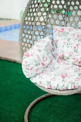 a white wicker chair with floral pillows on a green carpet at Hidden Leaf Private Resort in Dasmariñas
