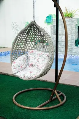 a wicker swing with a pillow on a green rug at Hidden Leaf Private Resort in Dasmariñas