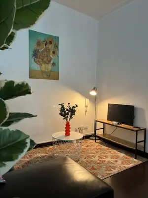 a living room with a table and a television at Spacious 2BR Mid- Century Modern Home at Gramercy Residences in Manila