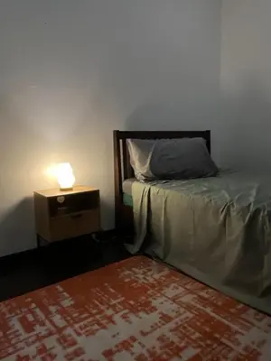 a bedroom with a bed and a night stand with a lamp at Spacious 2BR Mid- Century Modern Home at Gramercy Residences in Manila