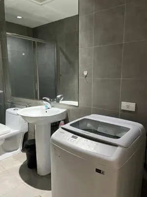 a bathroom with a sink and a washing machine in it at Spacious 2BR Mid- Century Modern Home at Gramercy Residences in Manila