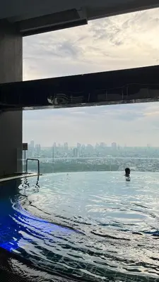 a person swimming in a pool of water at Spacious 2BR Mid- Century Modern Home at Gramercy Residences in Manila