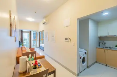 a kitchen and a living room with a table at CozyBGCCondoKing BedFast WiFiSteps fromUptownMall in Manila