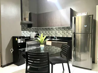 a kitchen with a glass table and a refrigerator at The Gramercy Residences by YYESS in Manila