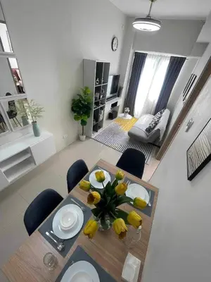 a living room with a dining room table with yellow flowers at Condo Transient by Eugenio Tan in Manila