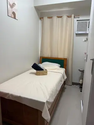 a small bedroom with a bed and a window at stylish 2BR Condo Near NAIA in Manila