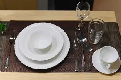 a table with white plates and forks and spoons at G & J Serene Suites in Tanza