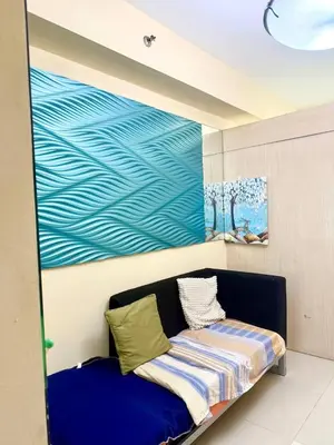 a blue couch in a room with a painting on the wall at Sea Residences Tower B Condotel Look F0R MaV in Manila