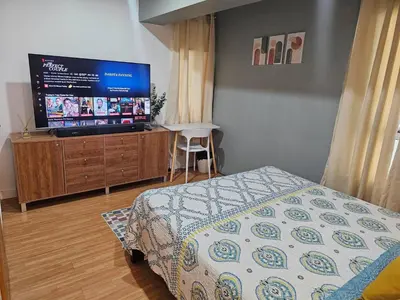 a bedroom with a bed and a flat screen tv at Casa Rosa2 2BR loft in BGC with 55 Smart TV 5 pax in Manila