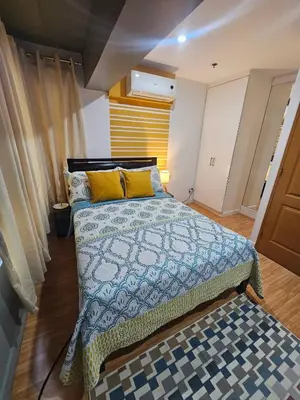 a bedroom with a bed with a blue comforter and yellow pillows at Casa Rosa2 2BR loft in BGC with 55 Smart TV 5 pax in Manila