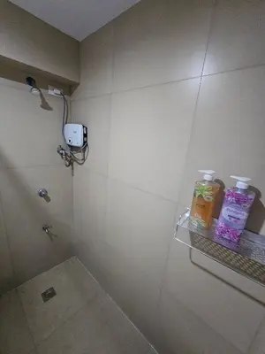 a bathroom with a shower with two bottles on a shelf at Casa Rosa2 2BR loft in BGC with 55 Smart TV 5 pax in Manila