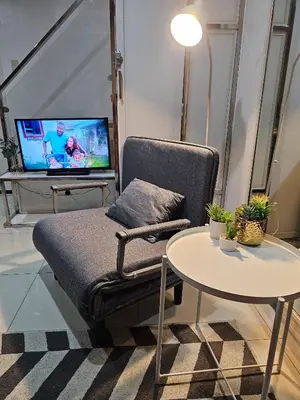 a living room with a chair and a table and a tv at Casa Rosa2 2BR loft in BGC with 55 Smart TV 5 pax in Manila