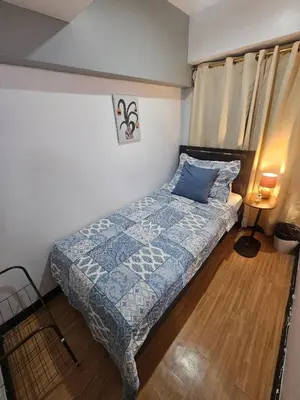 a small bedroom with a bed with a blue comforter at Casa Rosa2 2BR loft in BGC with 55 Smart TV 5 pax in Manila