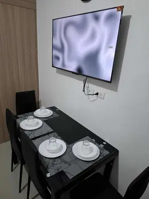a black table with four chairs and a tv on a wall at Oasis at Shore Residences in Manila