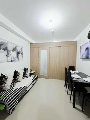a living room with a table and a dining room at Oasis at Shore Residences in Manila