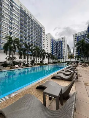 a large swimming pool with chairs and buildings at Sea Residences - Mall of Asia 829B by Forever-mc Condotel in Manila