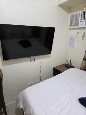 a bedroom with a large flat screen tv on the wall at Staycation All In in Manila