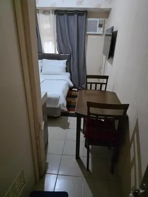 a small room with a bed and a table and chairs at Staycation All In in Manila
