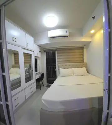 a small bedroom with a bed and a mirror at 1BR Deluxe Suite pool view with Balcony in Manila