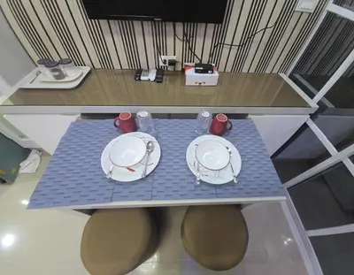 a table with plates and bowls on top of it at 1BR Deluxe Suite pool view with Balcony in Manila