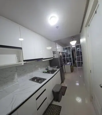 a small kitchen with white cabinets and a sink at 1BR Deluxe Suite pool view with Balcony in Manila