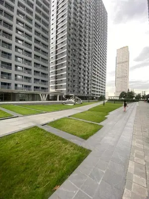 a person walking down a sidewalk with tall buildings at Fame Residences Staycation in Manila