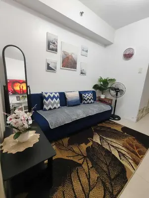 a living room with a blue couch and a table at Juliza's MOA Staycation in Manila