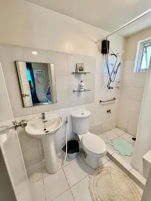 a white bathroom with a toilet and a sink at Jin's Jaunt in Manila