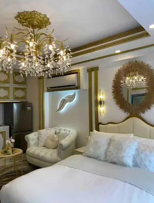 a bedroom with a bed and a couch and a chandelier at Royal Studio in Manila