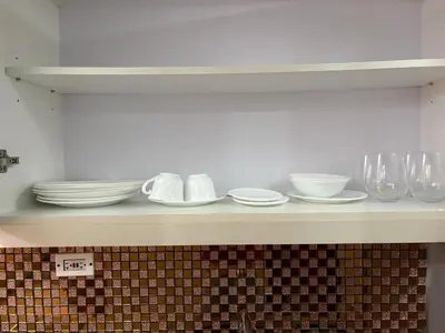 a shelf with plates and bowls and glasses on it at Elegant BGC 1BR Staycation One Uptown Residence in Manila