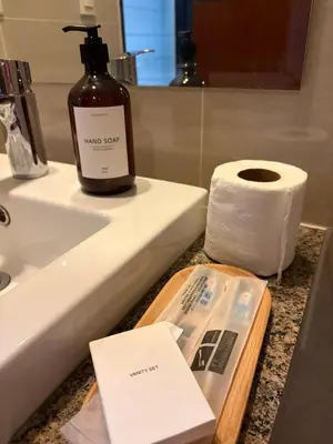 a bathroom sink with a bottle of soap and a roll of toilet paper at Elegant BGC 1BR Staycation One Uptown Residence in Manila