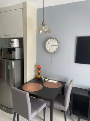 a dining room table with chairs and a clock on the wall at Comfy Studio for 2 at Sunshine100 in Mandaluyong Fully equipped in Manila